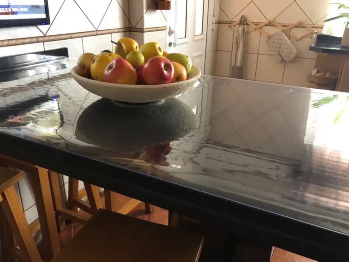 Kuchenny półwysep z blatem w marmurowym wzorze — misa jabłek i gruszek stoi na macie